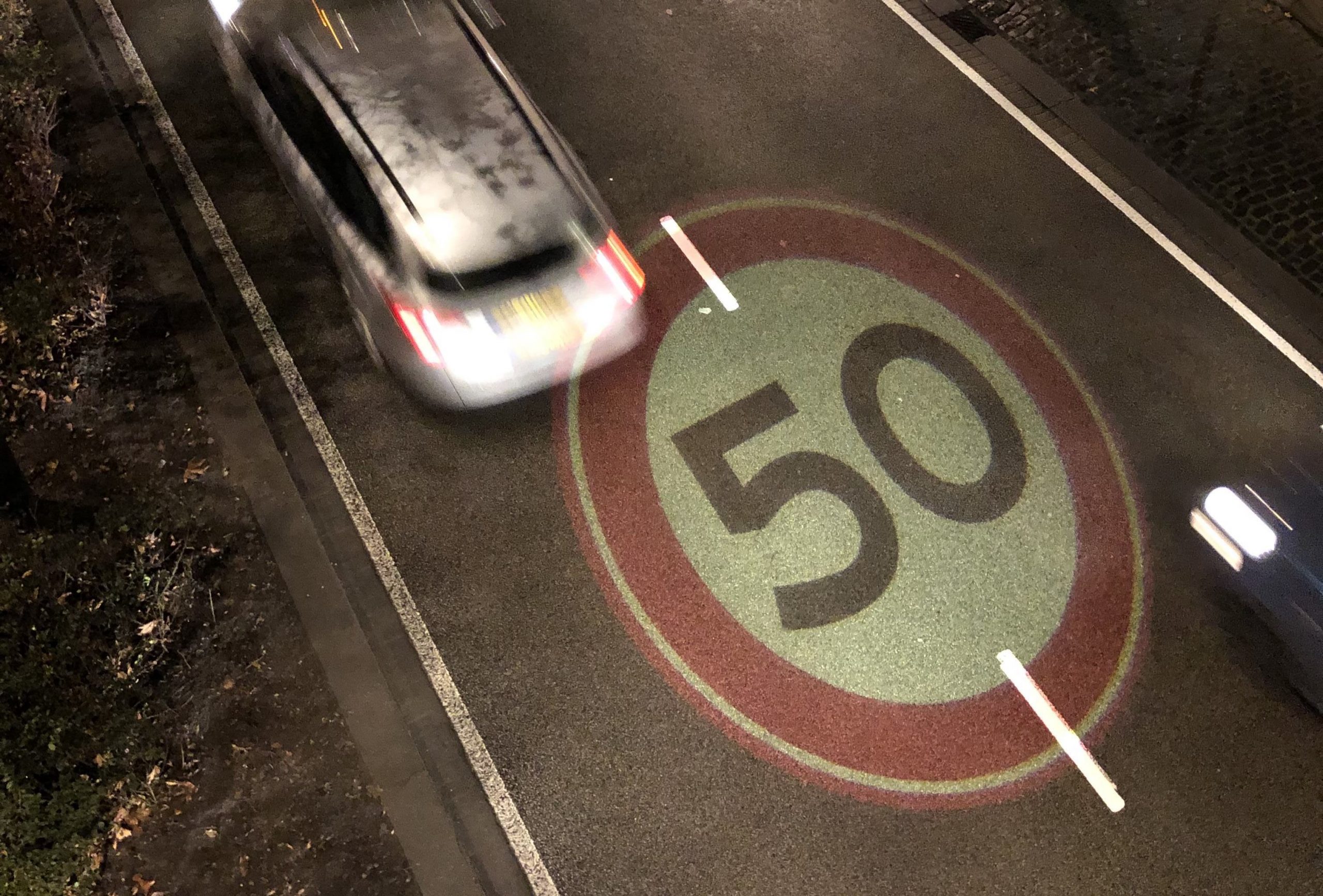 Auto rijdt over een 50-weg: goede verlichting is belangrijk in het verkeer